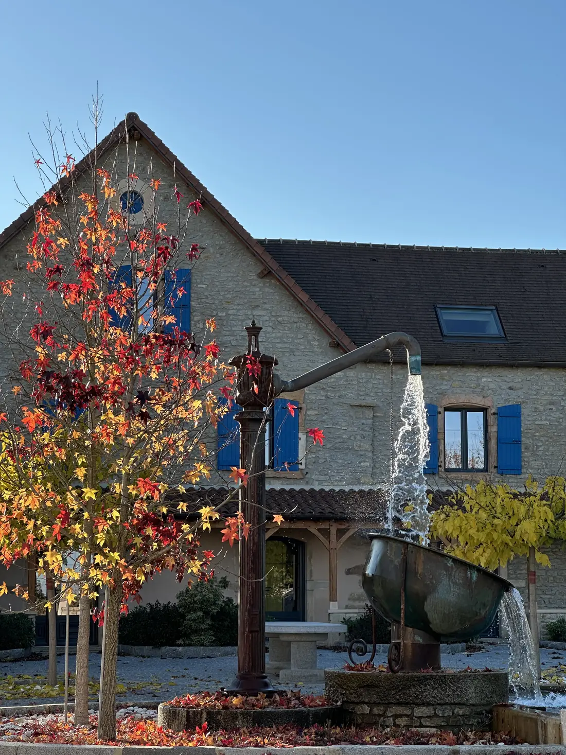 Une maison en pierre et sa fontaine, à l'automne